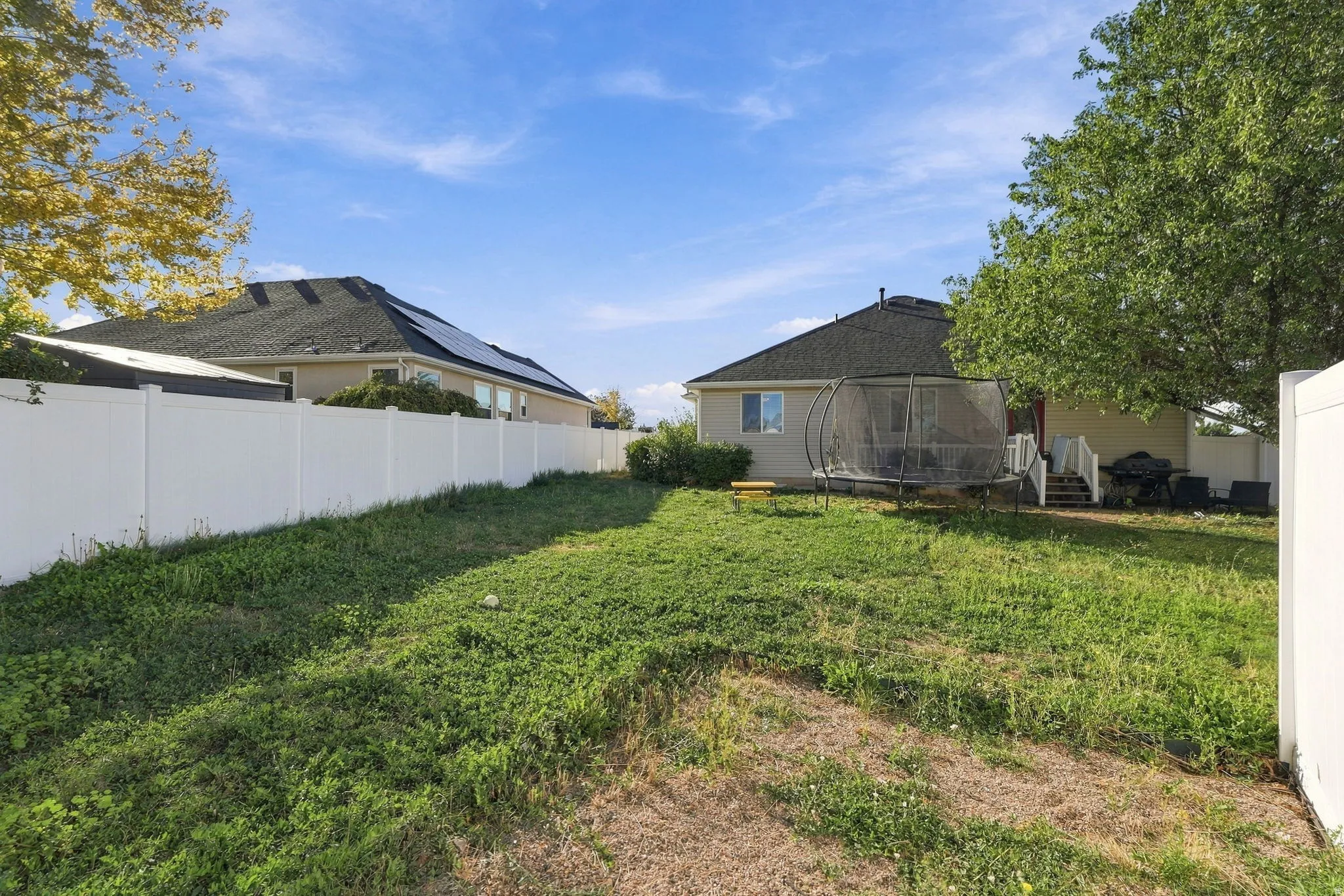 Expansive backyard with a white privacy fence and a rear patio