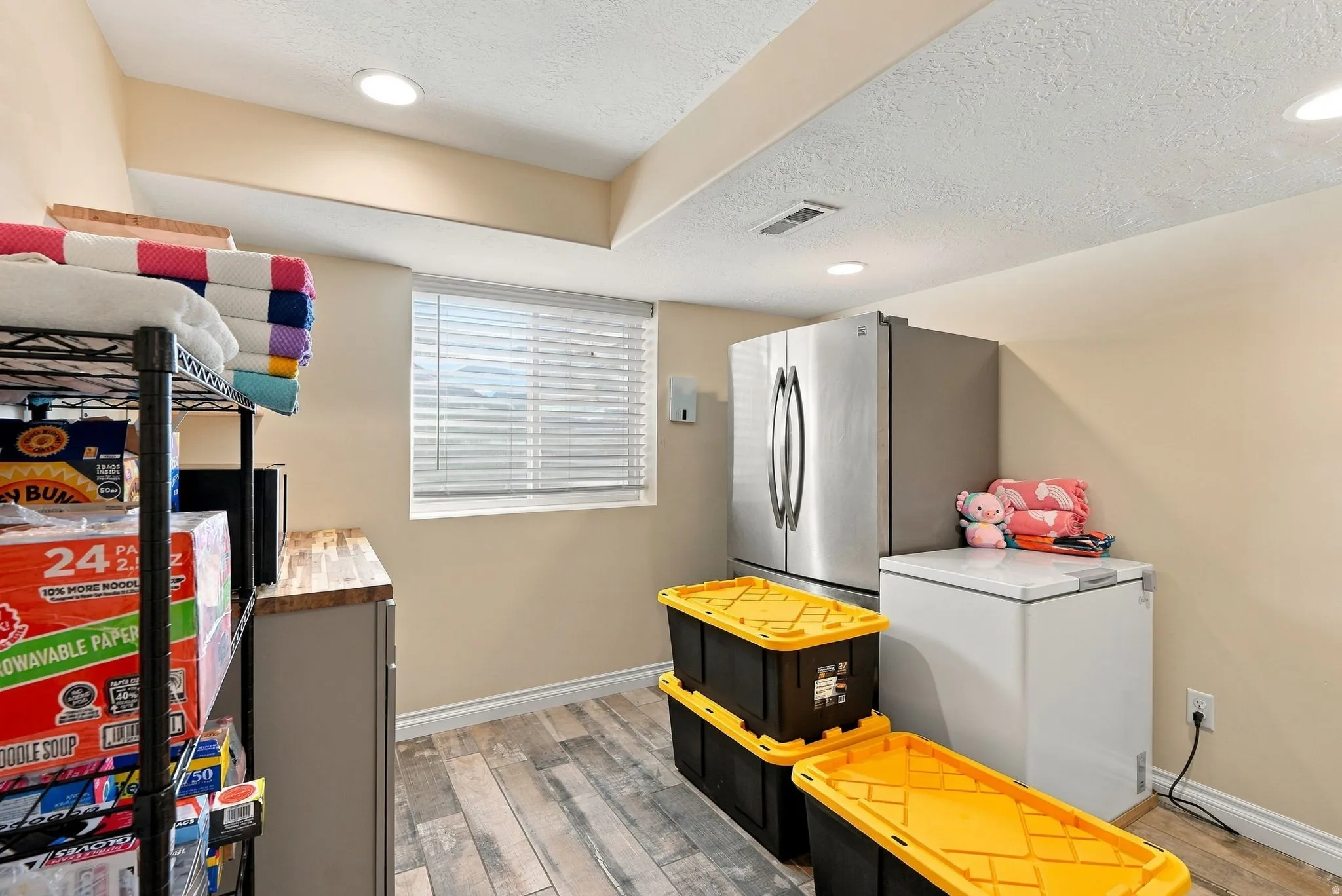 Recessed lighting illuminates the space, featuring wood-finish flooring and a window with horizontal blinds
