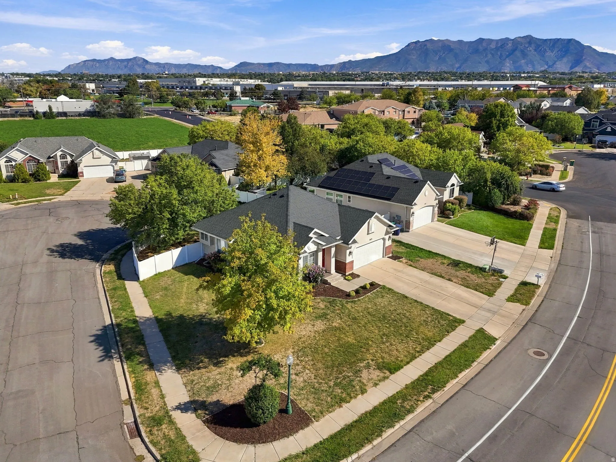 Property featuring a paved driveway, mature trees, and a mountain backdrop