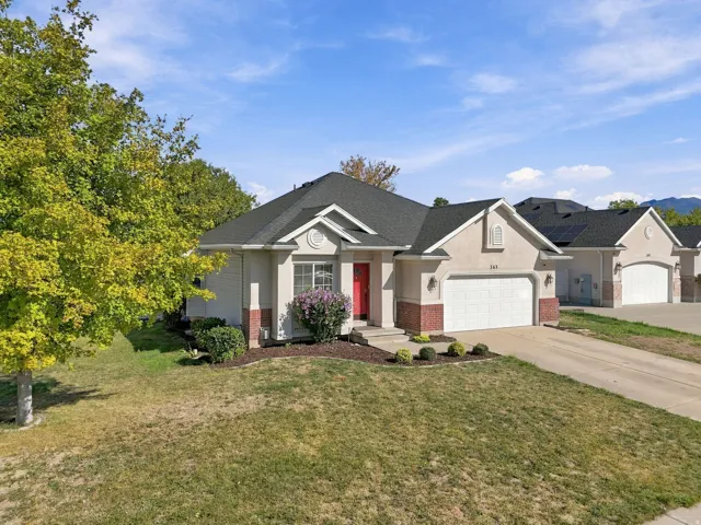Exterior featuring a two-car garage with white panel doors, red brick accents, and a red entry door