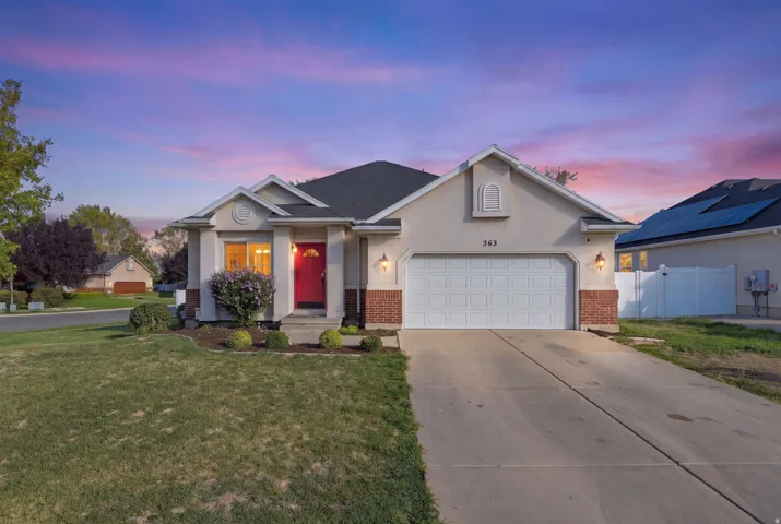 Stucco exterior with brick accents, attached two-car garage, and a red front entry door