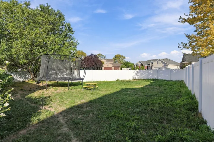 Expansive backyard with a white privacy fence and established trees