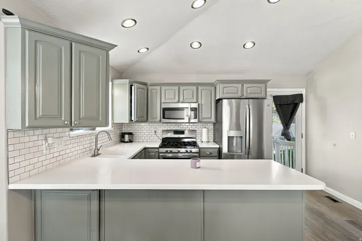 Kitchen featuring light gray cabinetry, white countertops, subway tile backsplash, stainless steel appliances, and recessed ceiling lighting