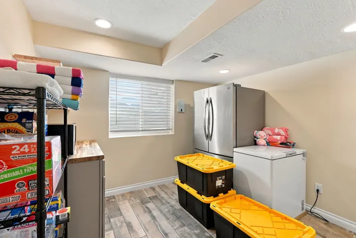 Recessed lighting illuminates the space, featuring wood-finish flooring and a window with horizontal blinds