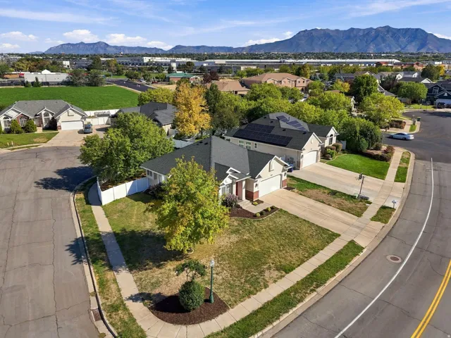 Property featuring a paved driveway, mature trees, and a mountain backdrop