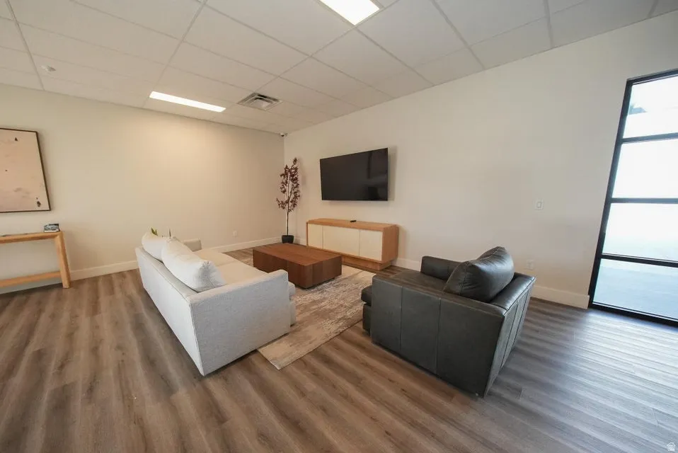 Wood-finish flooring with white baseboards, recessed lighting, and large window with dark frame