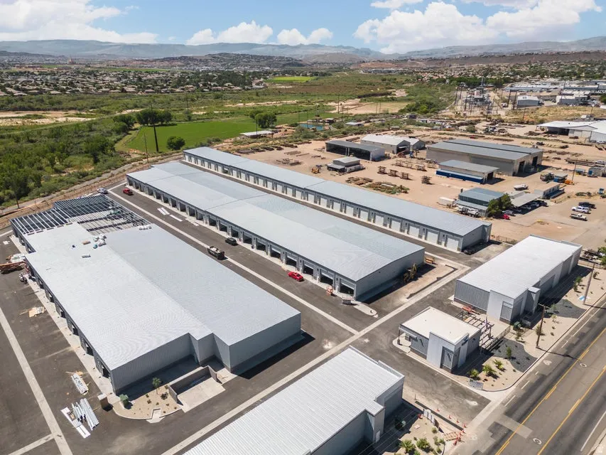 Multiple commercial buildings with metal roofing, paved parking areas, and surrounding desert landscaping