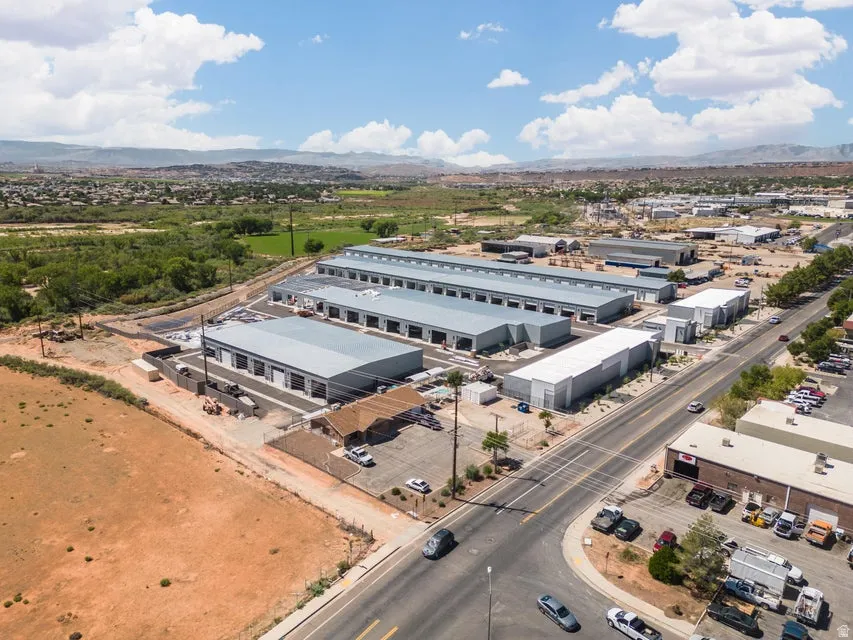 Industrial complex with multiple buildings, paved roadways, and a gravel lot