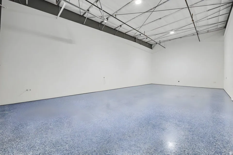 Spacious room featuring light-colored walls and a textured blue floor