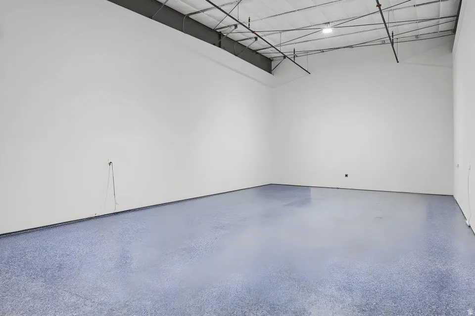 White walls with an exposed ceiling, featuring a polished concrete floor
