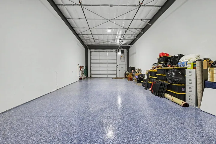 Epoxy flooring, high ceilings with exposed structural elements, and a large roll-up door