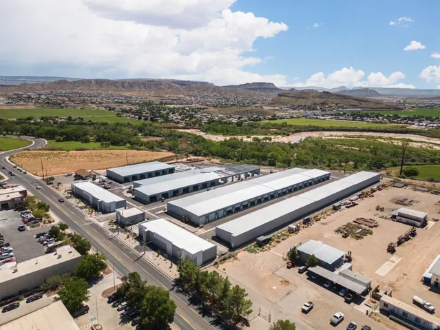 Multiple industrial buildings with grey metal roofing and large roll-up doors