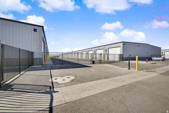 Metal-sided buildings with multiple roll-up doors, paved lot, and perimeter fencing