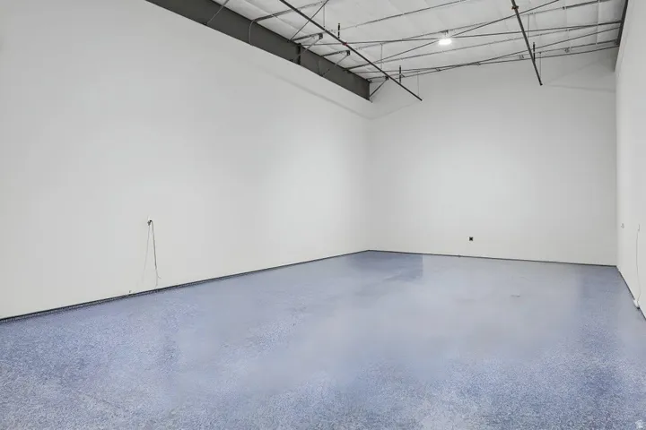 White walls with an exposed ceiling, featuring a polished concrete floor