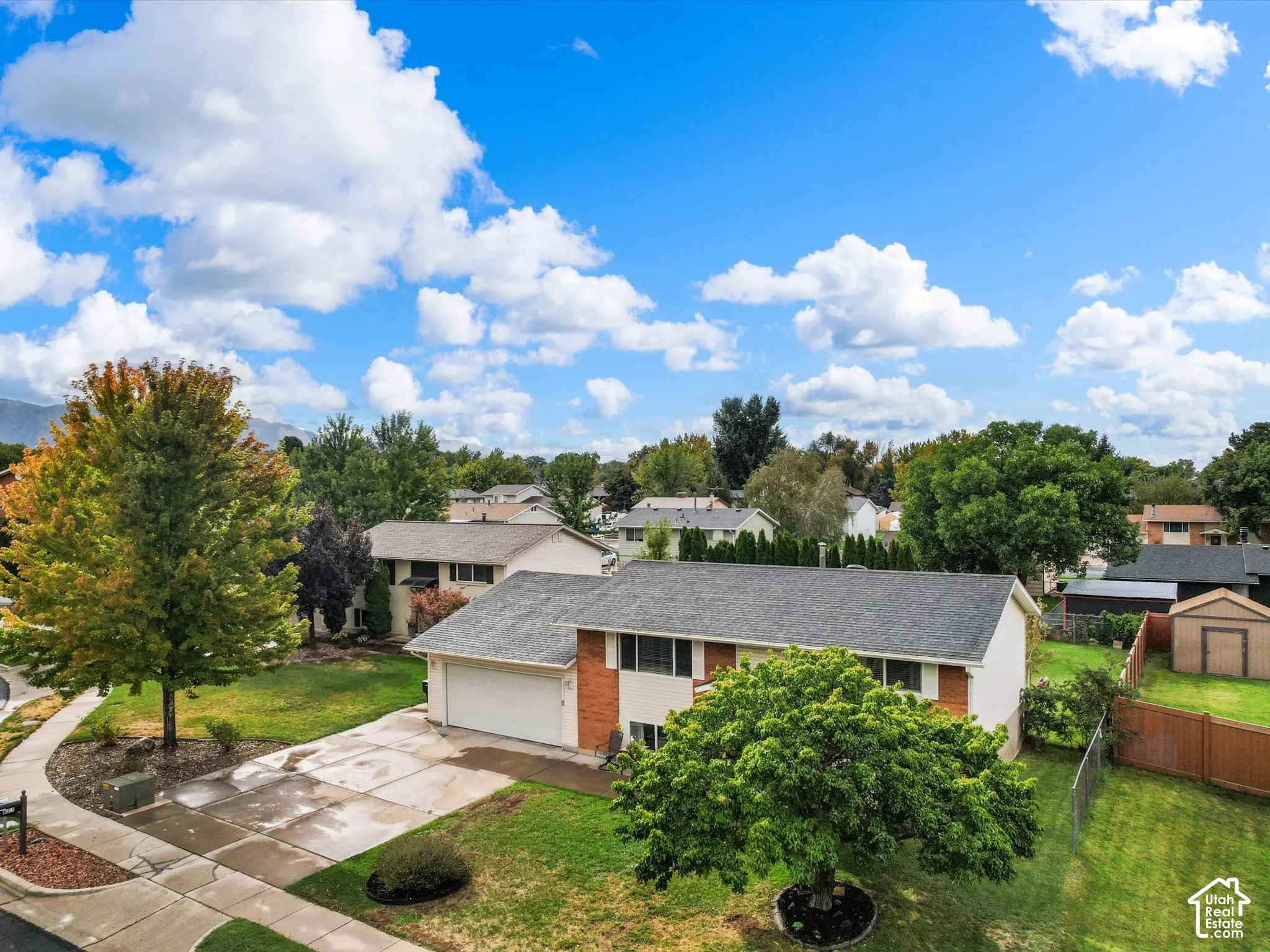 Split-level residence featuring an attached two-car garage, mature landscaping, and a fenced backyard