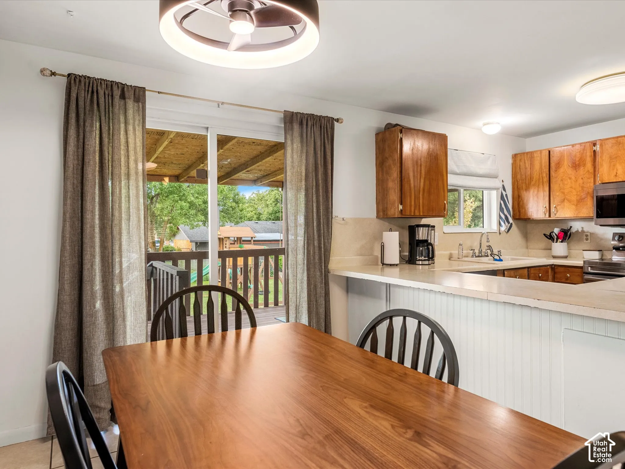 Eat-in kitchen featuring wood-finish cabinetry, light-toned countertops, and a full-height backsplash