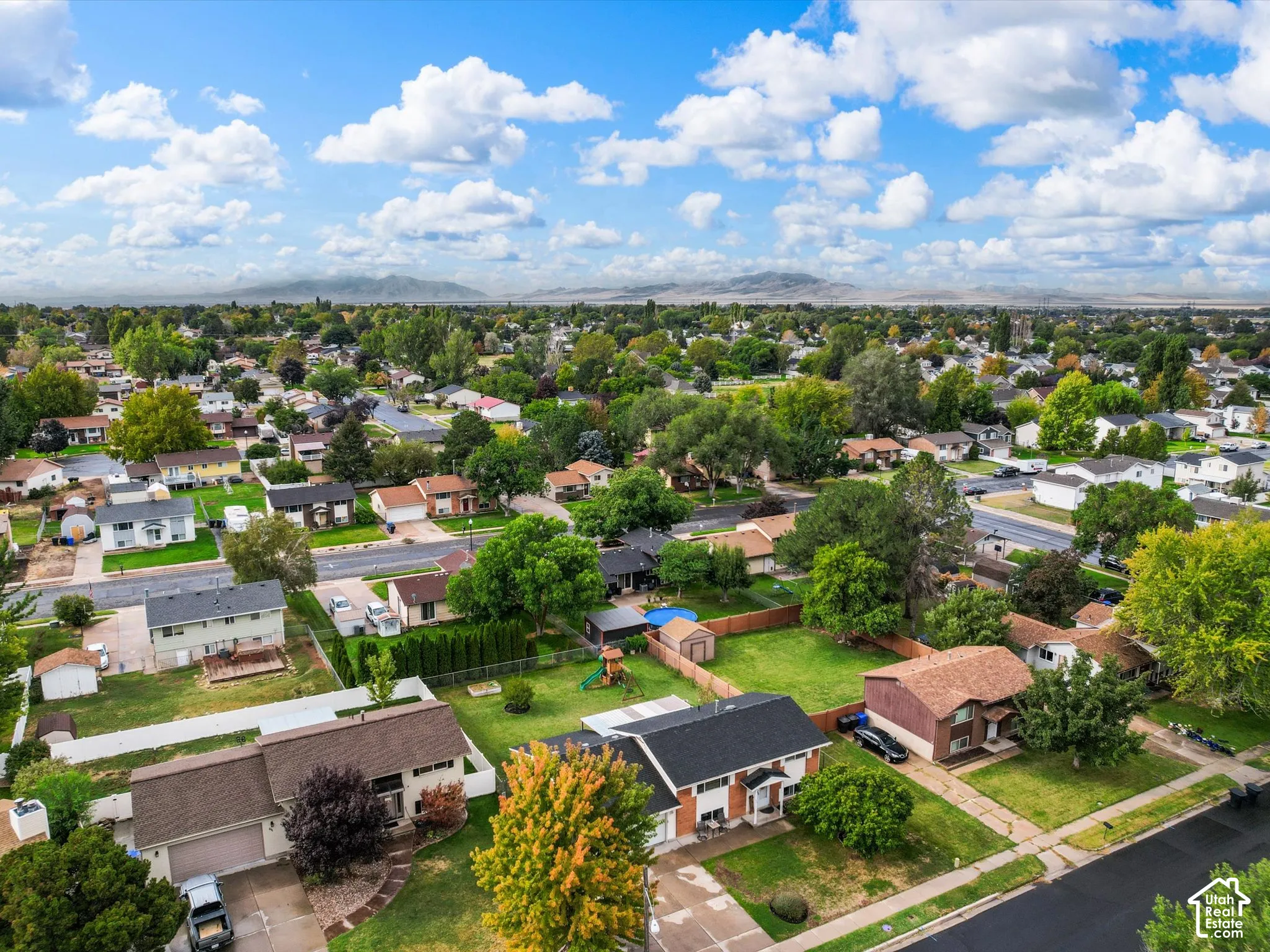 Expansive suburban neighborhood featuring numerous single-family homes, mature trees, and mountainous surroundings