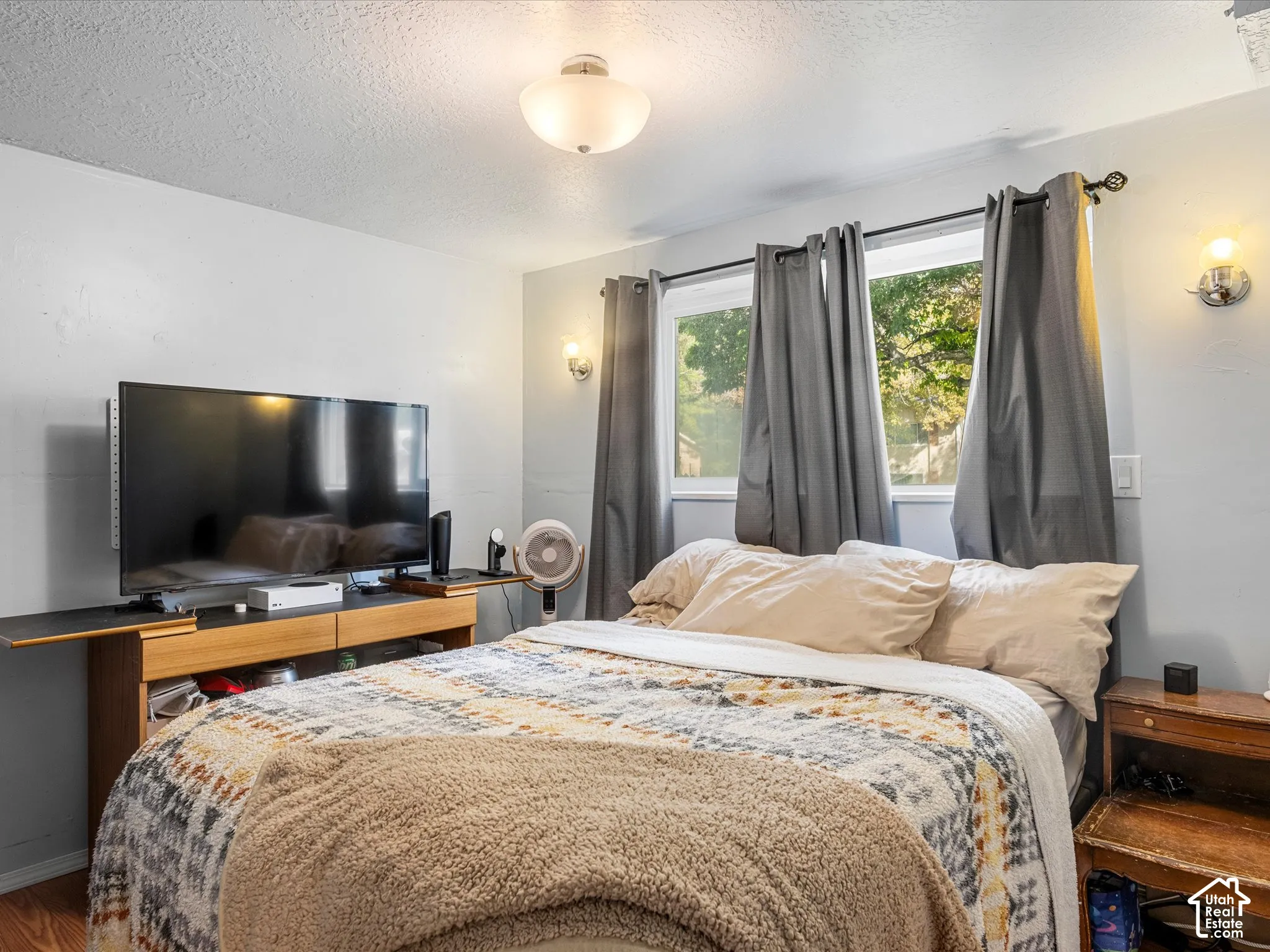 Recessed window with exterior scenery, wall-mounted sconce lighting, and wood-finish flooring