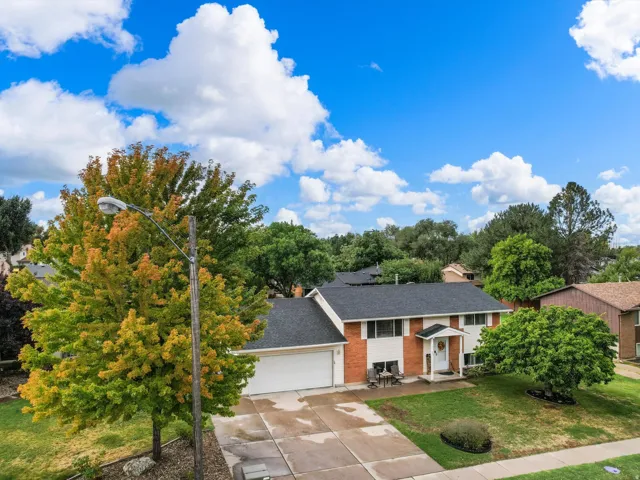 Two-story residence featuring a brick and siding exterior, an attached garage, a paved driveway, and mature landscaping