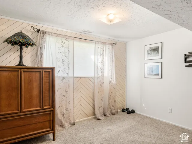 Neutral-toned carpeting paired with white walls, featuring a window with privacy blinds, and recessed lighting