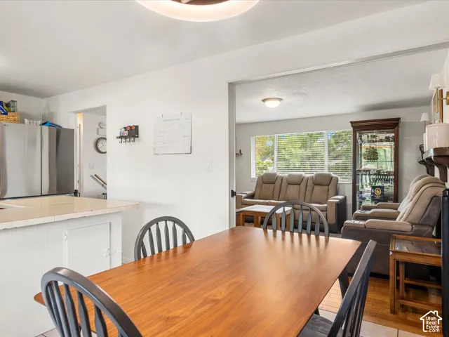 Dining area with a wood-finish table, adjacent to a living space featuring wood-finish flooring and a large window