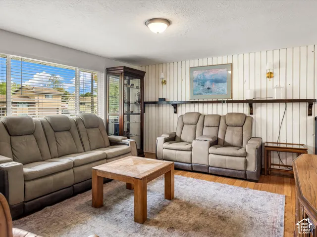 Hardwood flooring with a decorative area rug, large window with blinds, and built-in shelving