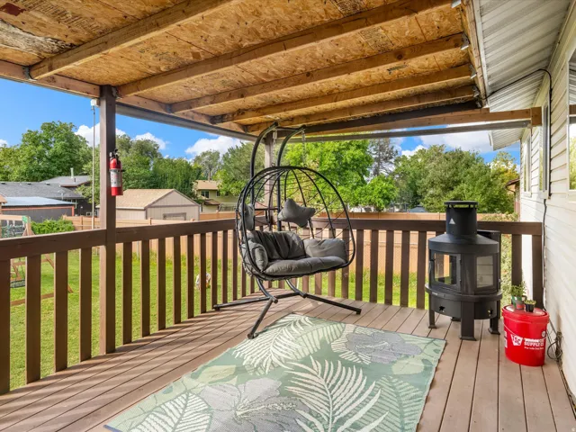 Covered outdoor deck with wood-finish flooring and a wood railing