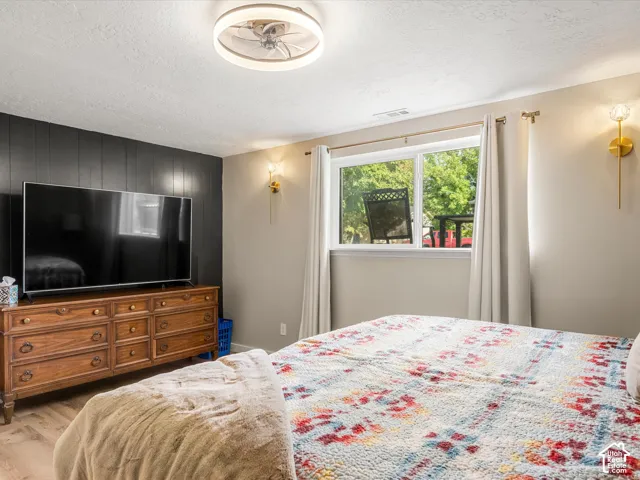 Recessed ceiling fan with integrated lighting, a contrasting accent wall, natural light from a double window, and two wall-mounted sconces