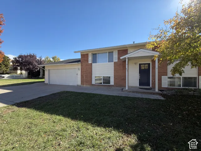 Split-level exterior featuring a brick and vinyl siding facade, covered entryway, multi-pane front door, and attached two-car garage