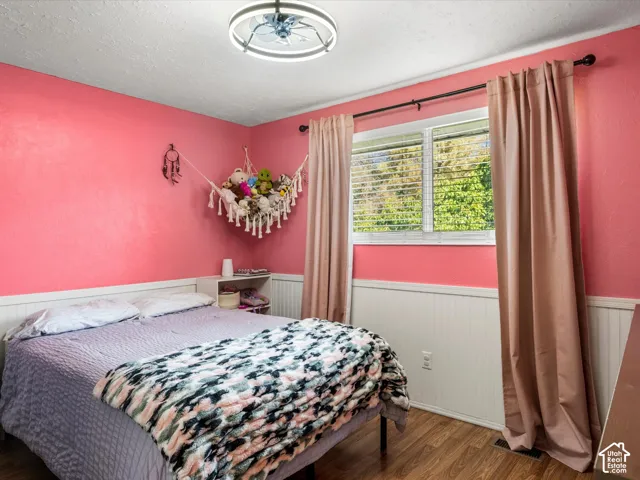 Wood-finish flooring, white beadboard wainscoting, and a ceiling fan with integrated lighting