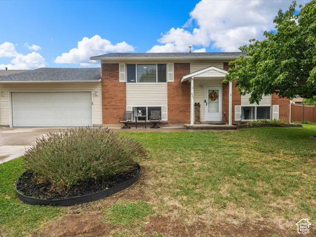 Brick and siding exterior with an attached garage, covered entry, and front yard landscaping