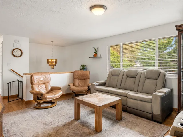 Warm wood-finish flooring, a contemporary overhead light fixture, and large windows with blinds