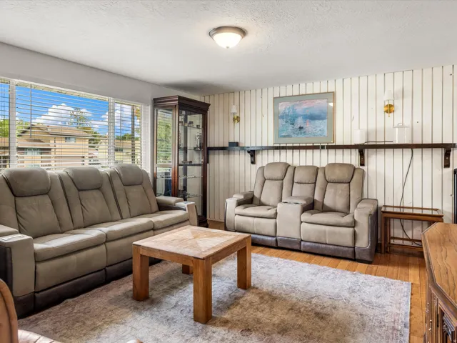 Hardwood flooring with a decorative area rug, large window with blinds, and built-in shelving