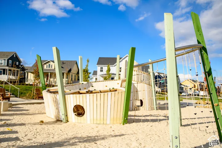 Neighborhood playground featuring a sand surface, wooden play structure, and integrated climbing ropes