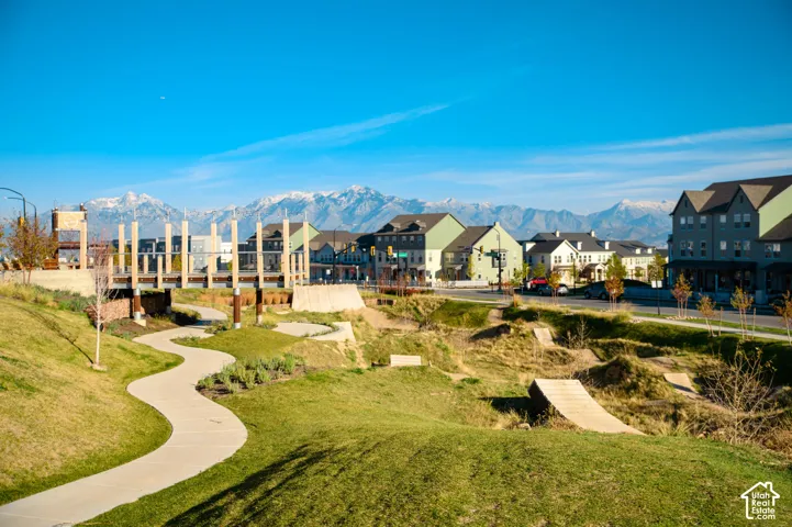 Winding pedestrian pathway, landscaped green spaces, and a pedestrian bridge over a dry creek bed