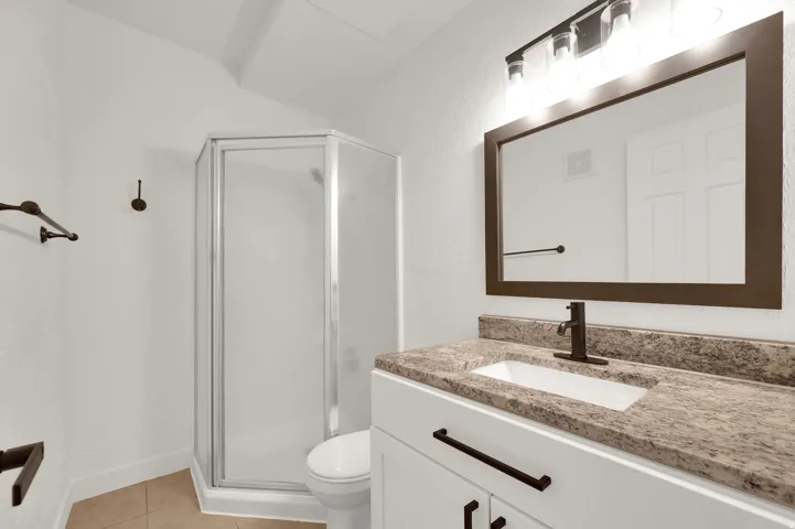 White vanity with a neutral-toned countertop, rectangular undermount sink, and matte black faucet