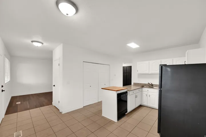 Kitchen featuring an island with wood-finish countertop, white cabinetry, and light-toned tile flooring
