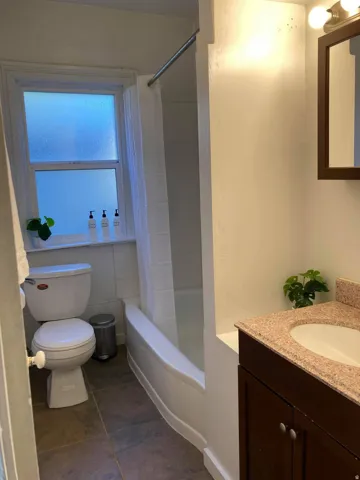 Integrated vanity with a composite countertop and undermount sink, a framed mirror, and a white porcelain toilet