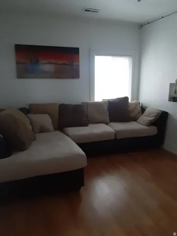 Wood-finish flooring with white walls and a window with blinds