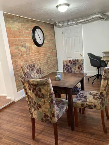 Exposed brick wall, wood-finish flooring, recessed ceiling light fixture, white interior door, visible ductwork