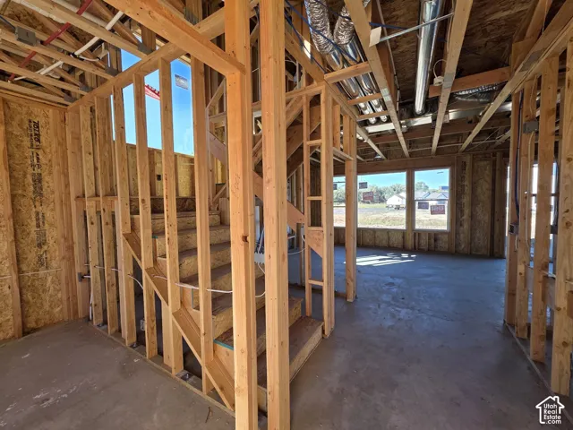 Framed interior structure with exposed wooden studs, a staircase, and concrete flooring