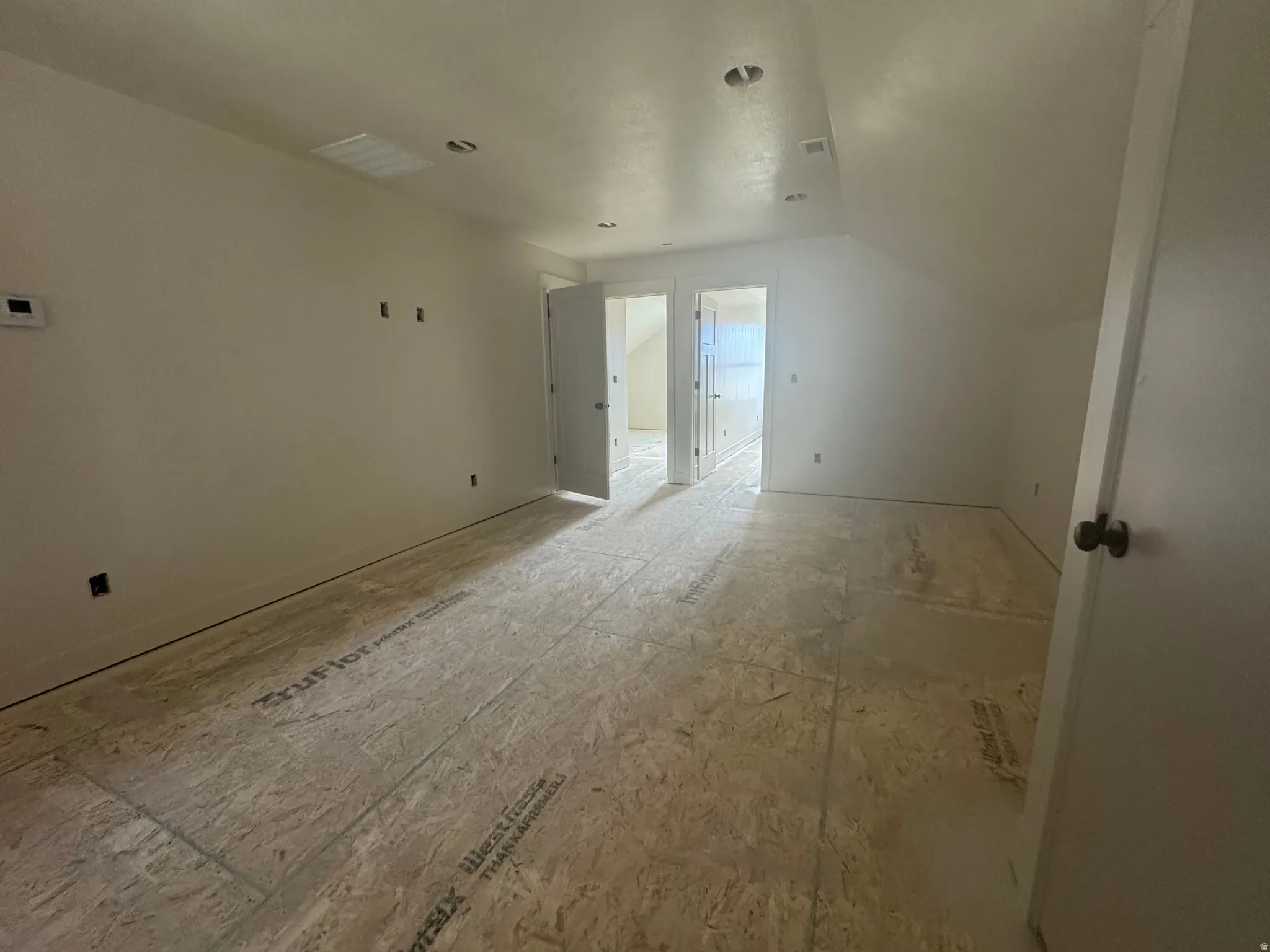Unfinished flooring, white walls, recessed ceiling lighting, and a sloped ceiling
