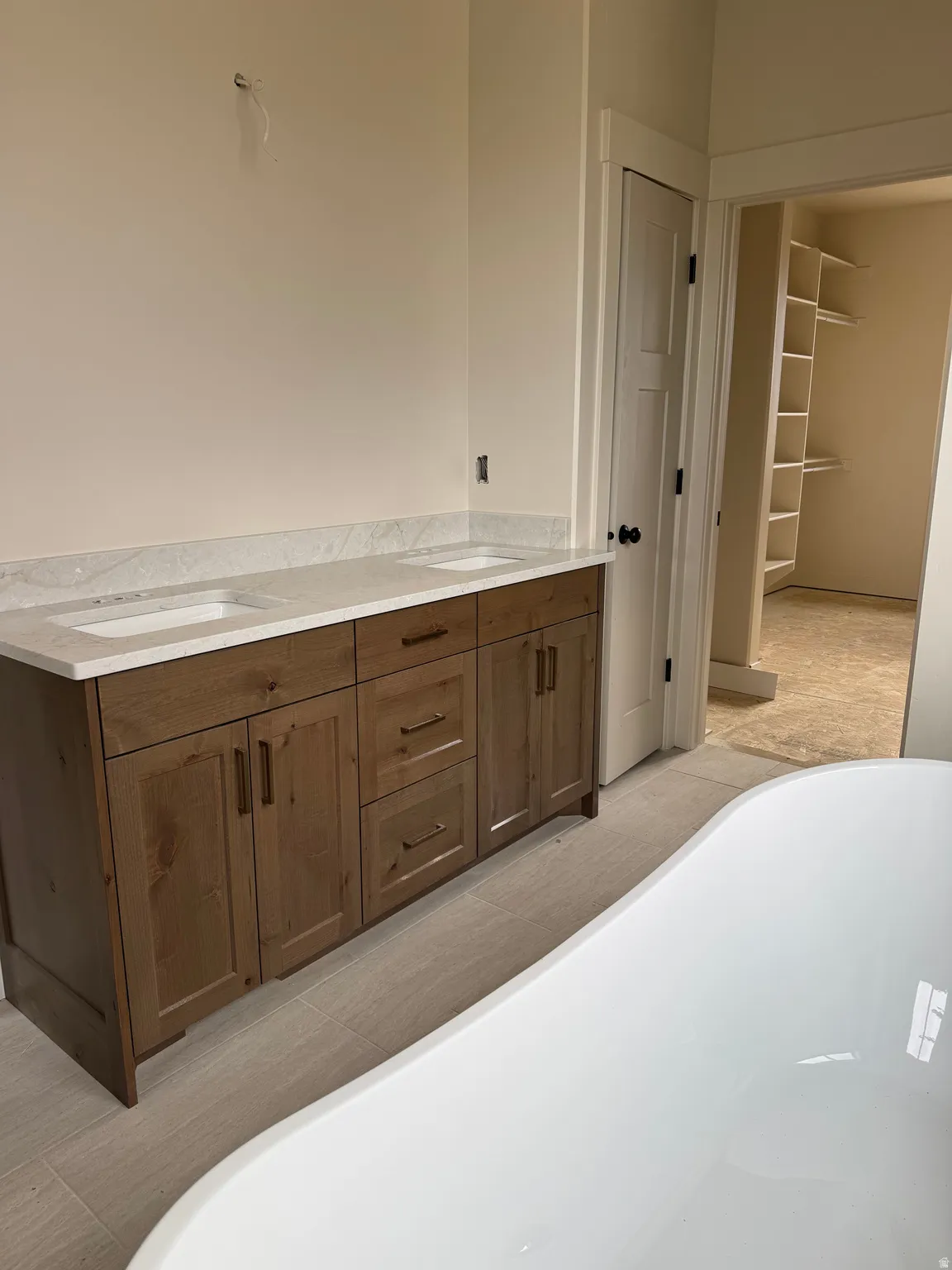Dual vanity with wood-finish cabinetry, light-toned countertops, and undermount sinks