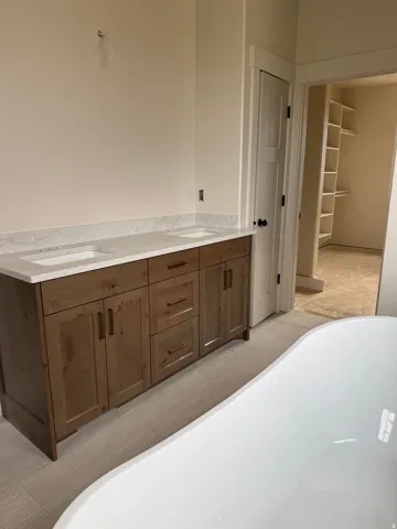 Dual vanity with wood-finish cabinetry, light-toned countertops, and undermount sinks