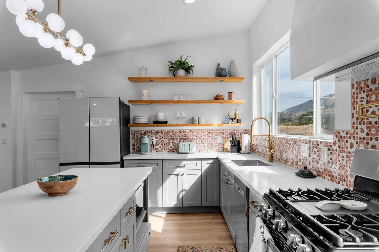 Guest house kitchen featuring a gas range, stainless steel appliances, a white island, and light wood-finish flooring