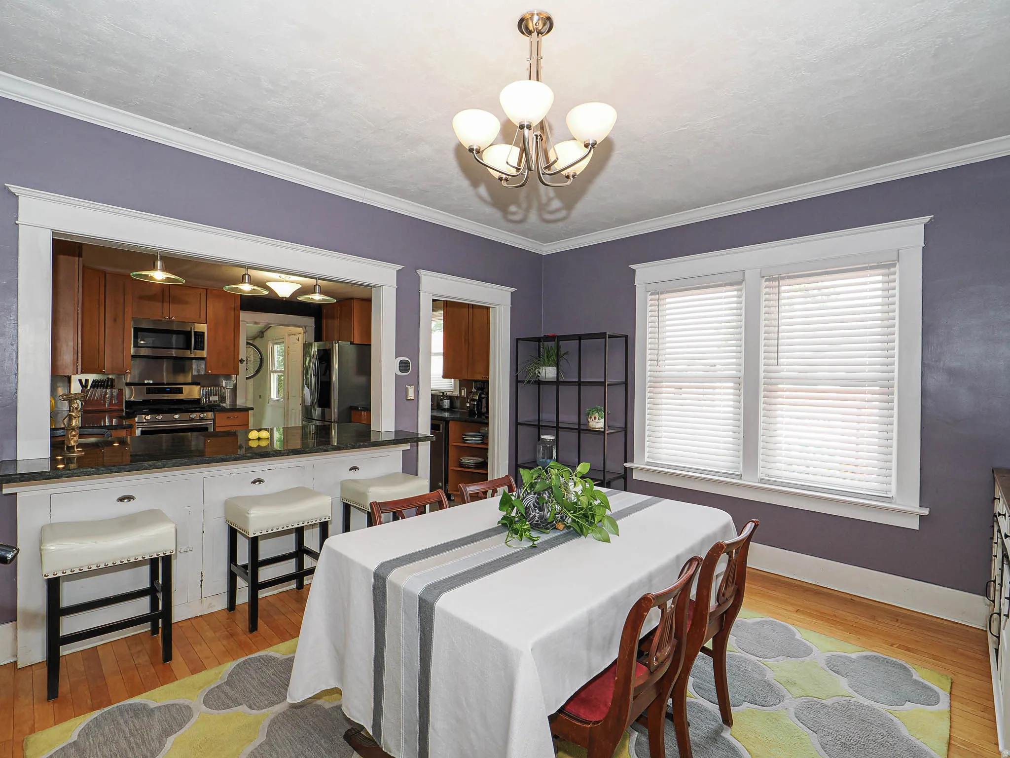 Wood-finish flooring, white crown molding, and a five-light chandelier