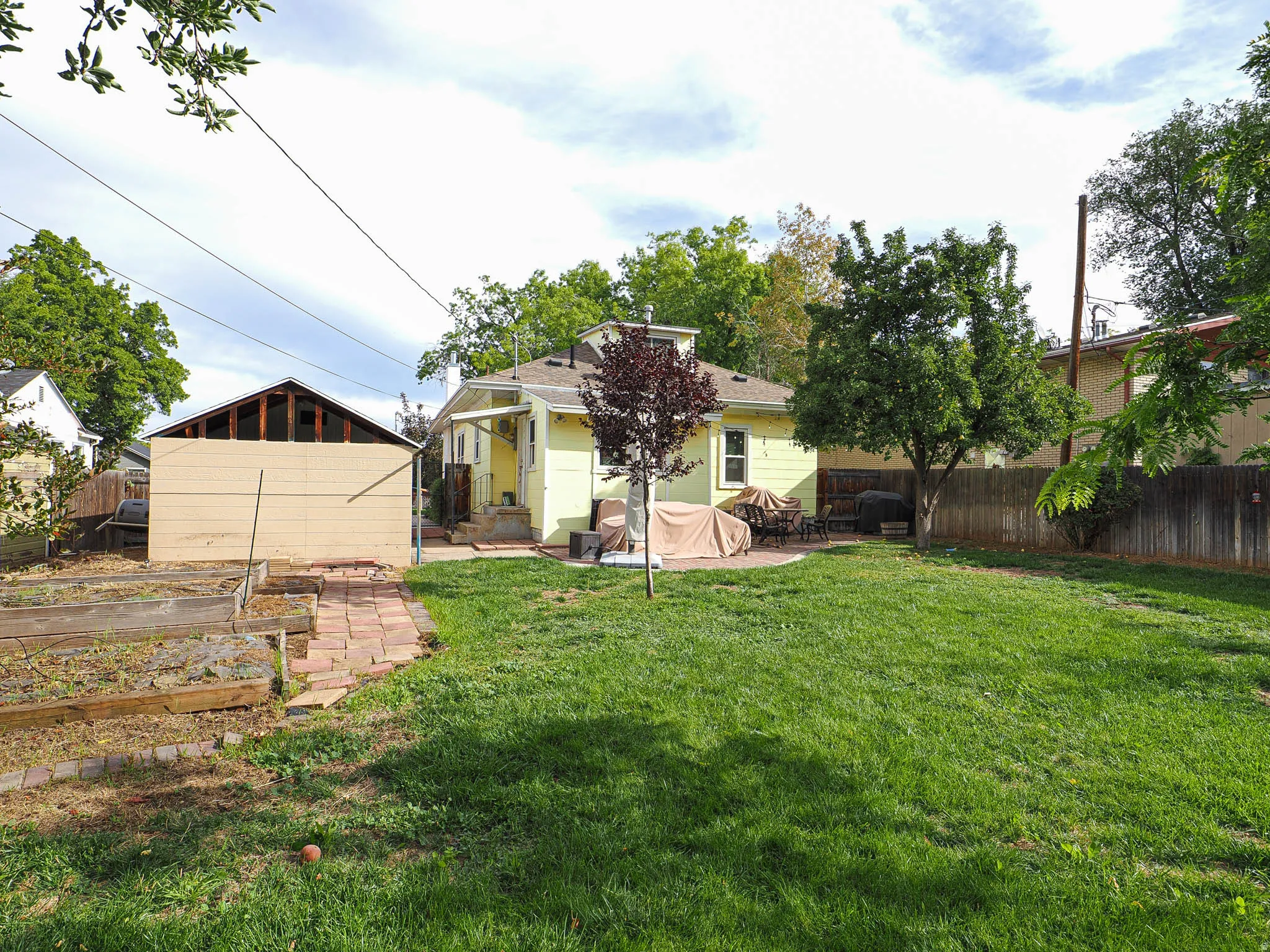 Expansive green lawn with a paver patio and mature trees