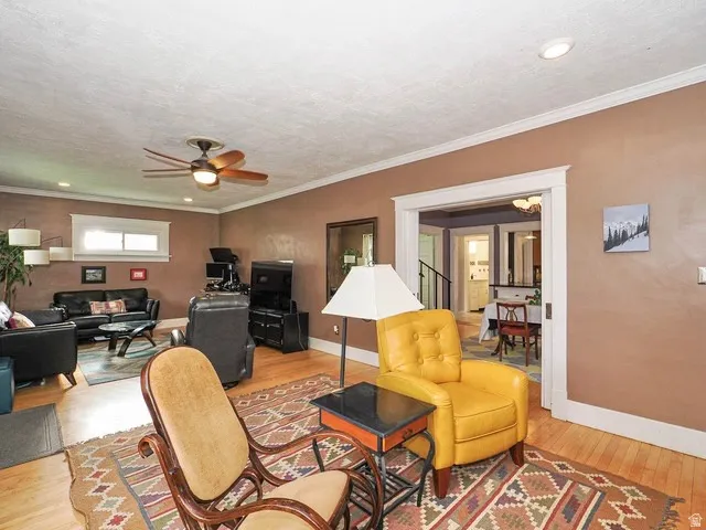 Hardwood flooring, crown molding, ceiling fan, recessed lighting, and a wide doorway