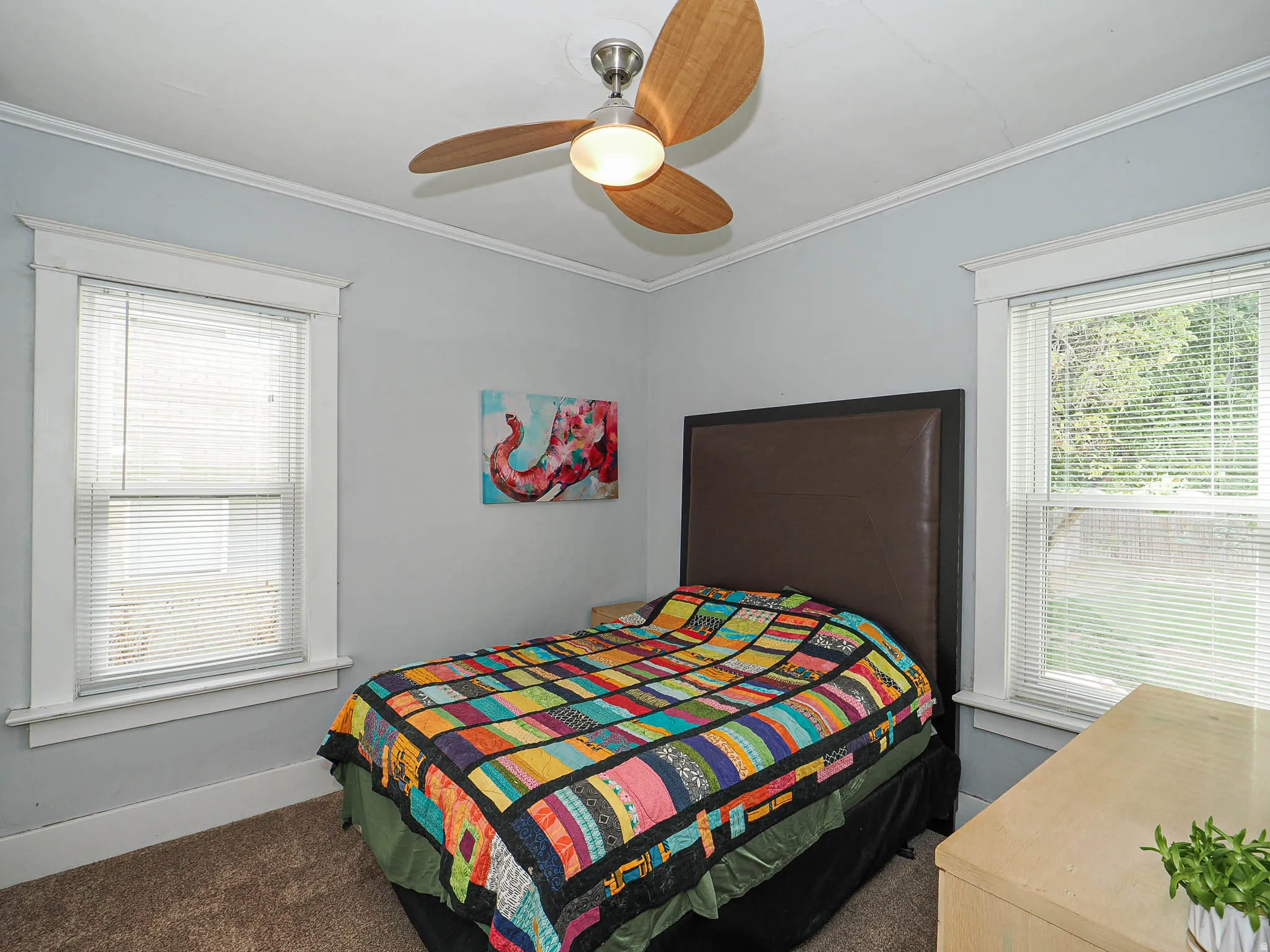 Light gray wall paint, crown molding, two windows with blinds, and a ceiling fan with wooden blades