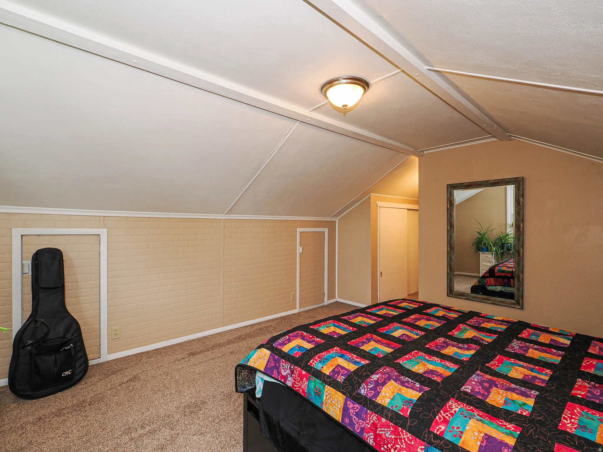Sloped ceilings, wall-to-wall carpeting, and a flush-mount ceiling light